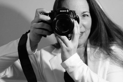 Frau mit langen dunklen Haaren fotografiert mit einer Sony-Kamera. Schwarzweißfoto, weiße Bluse.