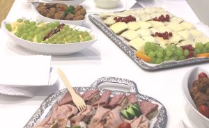 Langer weißer Buffettisch mit verschiedenen Platten: Aufschnitt, Käse, Weintrauben, Fleischbällchen und weiteren Speisen.