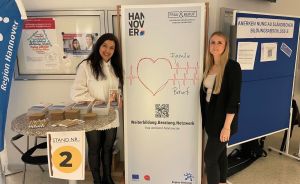 Zwei Frauen stehen an Stand Nr. 2 neben einem Hannover-Banner „Frau & Beruf" mit Herzmotiv und QR-Code.