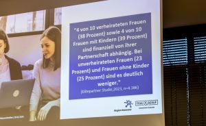 Präsentationsfolie auf Leinwand mit deutschem Zitat zur finanziellen Abhängigkeit von Frauen, Logo „Frau & Beruf Hannover Region".