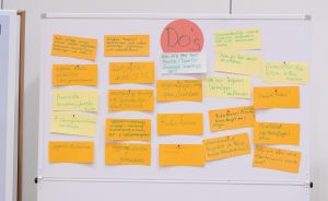 Whiteboard mit orangefarbenen Post-its auf Deutsch zum Thema „Do's", handschriftlich beschriftet.