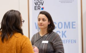 Zwei Frauen im Gespräch vor einem Banner mit „Welcome Back" und dem Logo der Region Hannover.